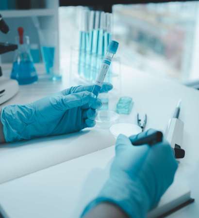 Un químico toma notas sobre los datos de la investigación mientras el científico trabaja en el laboratorio. El químico analiza los resultados experimentales y realiza anotaciones; ideas para el laboratorio